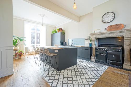 a kitchen with black appliances and a fireplace at Le Manoir Ducey - Mont-Saint-Michel in Ducey