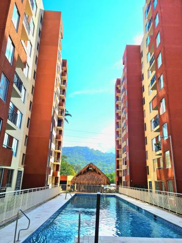 a swimming pool between two tall buildings at Oasis Panelero Apartamento Familiar Villeta in Villeta