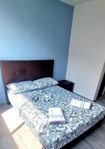 a bed in a bedroom with a blue wall at Oasis Panelero Apartamento Familiar Villeta in Villeta