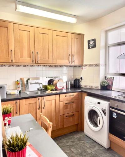 cocina con armarios de madera, lavadora y secadora en Central London zone 1 double room, en Londres