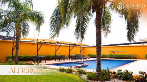 un complejo con piscina y palmeras en Altavista Hotel, en Reynosa