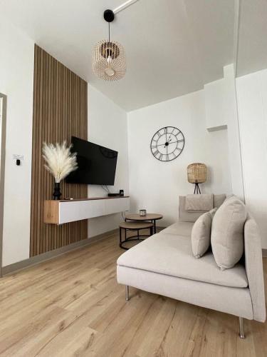 un salon avec un canapé et une horloge au mur dans l'établissement Charmant appartement avec terrasse et parking - Centre ville, à Chartres