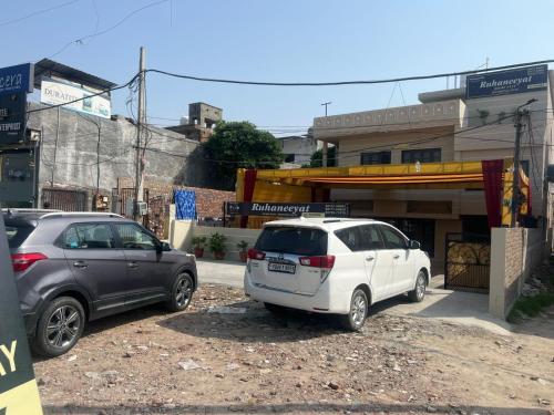 zwei Autos auf einem Parkplatz vor einem Gebäude geparkt in der Unterkunft Ruhaneeyat Home Stay in Amritsar