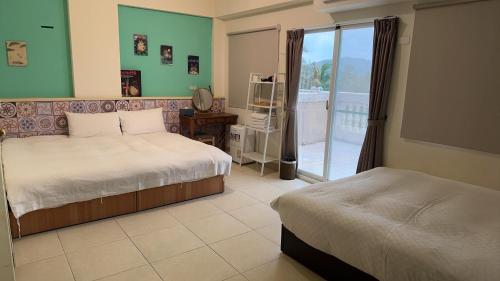 a bedroom with two beds and a sliding glass door at 海洋柔情-旅遊補助-日租 包棟-親子 寵物友善 溜滑梯 海洋公園 沙灘車 天空之鏡 in Jian