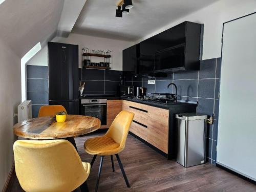 a kitchen with a wooden table and yellow chairs at Vila Citadella in Svitavy