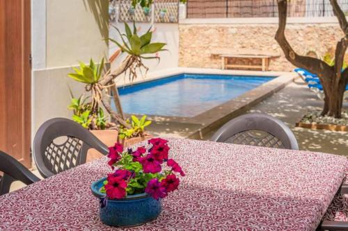 un tavolo con un vaso di fiori su un tavolo con una piscina di Sa Llimonera de Binissalem, piscina privada ideal familias, 6 dormitorios con aire acondicionado a Binissalem