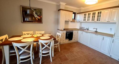 a kitchen with a wooden table and white cabinets at Созополис MORE SUN- Созопол in Sozopol