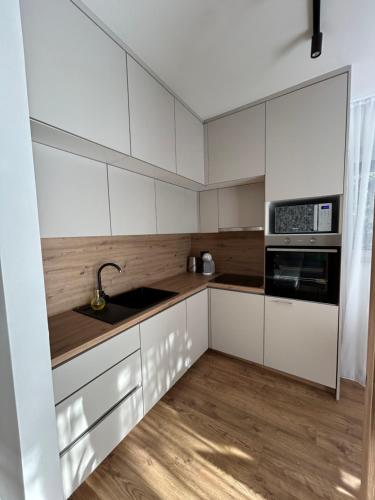a kitchen with white cabinets and a sink at GO Jahorina by Olympic Gardens in Jahorina