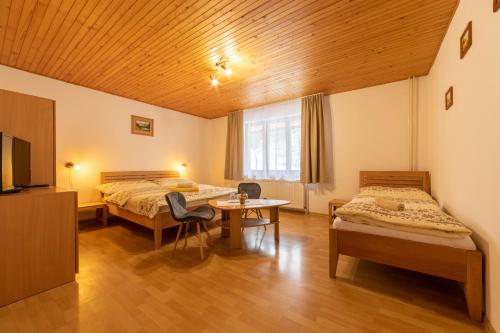 a room with two beds and a table and a tv at Penzión pod Kýčerou in Zuberec