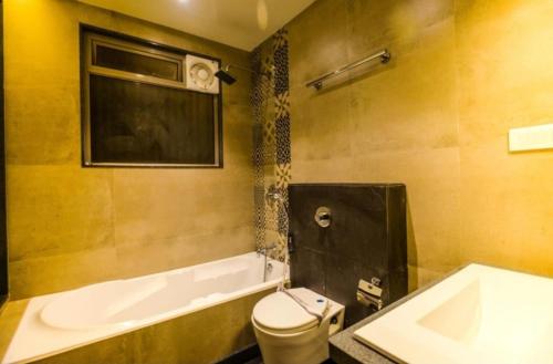 a bathroom with a tub and a toilet and a sink at Elite Boutique Hotel in Satara
