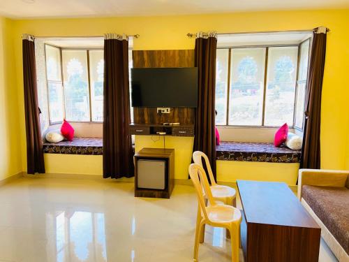 a living room with two windows and a table and chairs at Hotel Treasure OF Kumbhalgarh in Kumbhalgarh