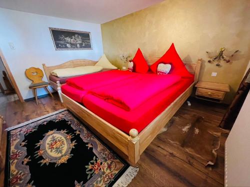 a bedroom with a large wooden bed with red pillows at Ferienwohnung Alpensymphonie mit 110 m2 und sonnigem Balkon in Burgberg