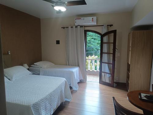 a bedroom with two beds and a door to a balcony at Flat Miguel Pereira in Miguel Pereira