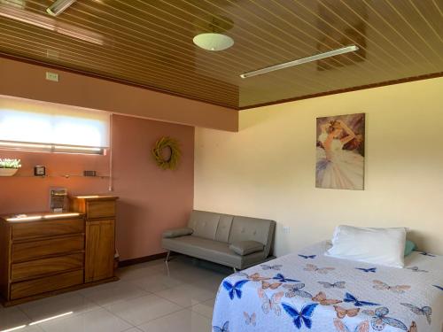 1 dormitorio con 1 cama y 1 silla en Disfruta del contacto con la naturaleza, en Puntarenas