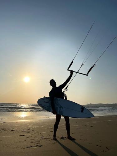 a man standing on the beach holding a surfboard at DEPARTAMENTO 5to piso CON VISTA AL MAR in Playas