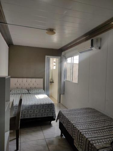 a bedroom with two beds and a table and a window at Casas Bravo in Itajaí