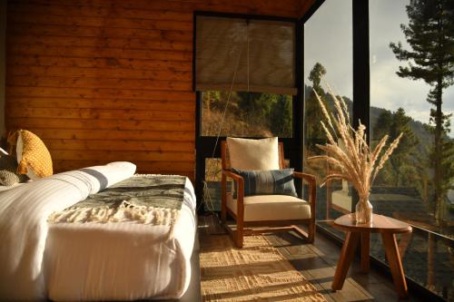 sypialnia z łóżkiem i krzesłem na balkonie w obiekcie Montane Chalet , Sethan w mieście Manāli