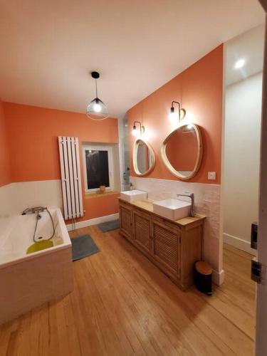 une salle de bain avec deux lavabos et deux miroirs dans l'établissement Maison dans le parc des volcans, à Saint-Genès-Champanelle