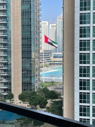 a red flag flying in front of tall buildings at Elegant New 2BR l Spacious with Burj & Fountain Views l near Dubai Mall l Pool l Gym in Dubai