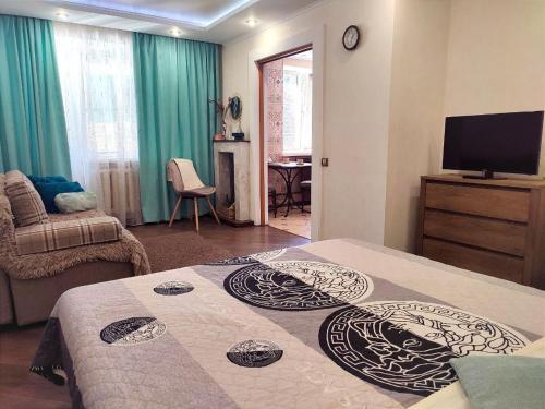 a bedroom with a bed and a television and a couch at Бирюзовый стиль in Chernihiv