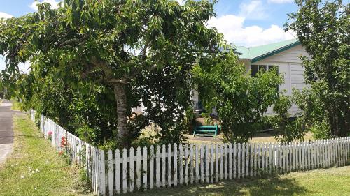 オークランドにあるGreen Getaway- Unique, 4 bedroom Bungalow Papakuraの木の家の前の白い柵