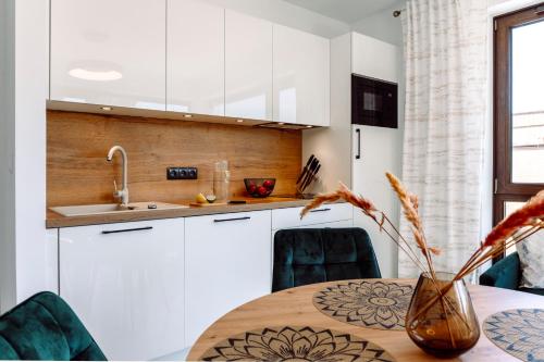 a kitchen with white cabinets and a table with a vase at Apartamenty Belni Hel Edyta i Maciej Wolak in Hel