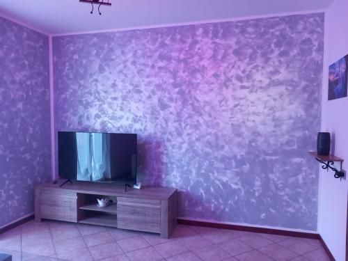 sala de estar con TV en una pared púrpura en A Home away From Home By Alex Appartamento Malpensa Prestige Residence en Busto Arsizio