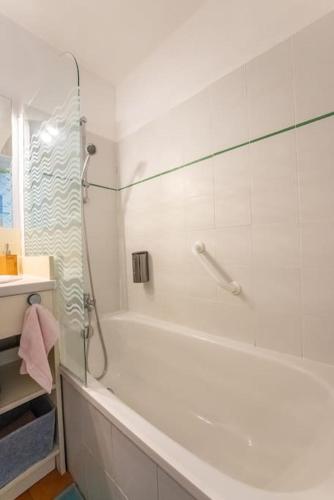 La salle de bains blanche est pourvue d'une douche et d'une baignoire. dans l'établissement Au calme, dans les pins, avec vue mer et piscine, à Sainte-Maxime
