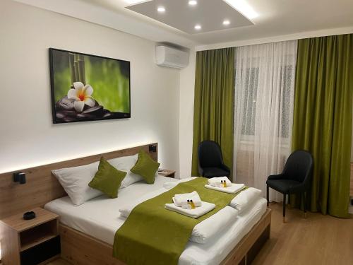 1 dormitorio con 1 cama grande con cortinas y sillas verdes en Inaya Apartman Free Parking, en Sarajevo