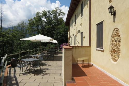 a patio with tables and chairs and an umbrella at B&B Dal Brillante in Seravezza