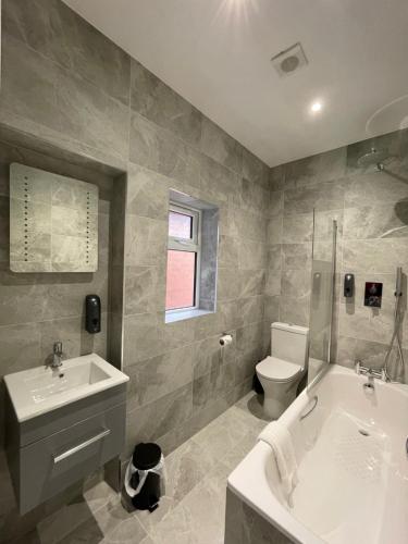 uma casa de banho com uma banheira, um WC e um lavatório. em Gainsborough Lodge em Horley