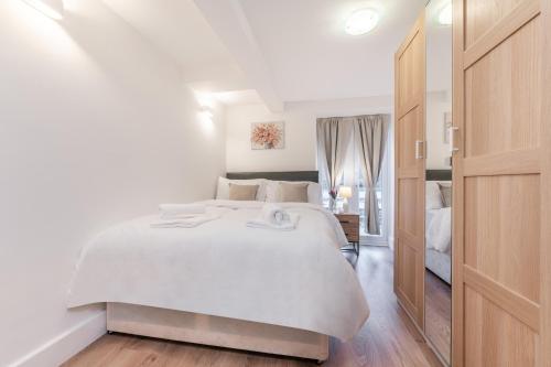Un dormitorio blanco con una gran cama blanca. en A Golden Haven Retreat in London, en Londres