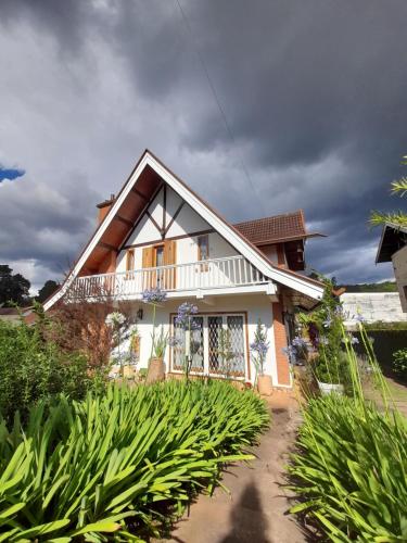 a house with a lot of plants in front of it at Suítes no Chalé - Cabanas in Campos do Jordão