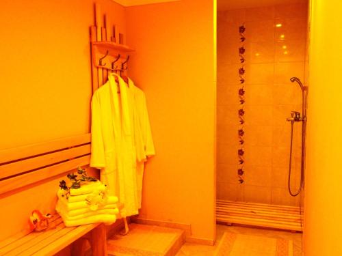 y baño con ducha y albornoz amarillo. en Šiaurės Vartai en Joniškis