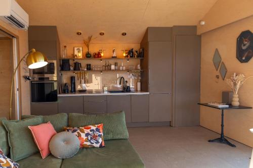 a living room with a green couch and a kitchen at L'Alrance del traouc in Bozouls