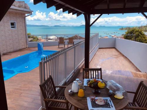 una mesa y sillas en un balcón con piscina en Casa mirante com piscina em Governador Celso Ramos, en Governador Celso Ramos