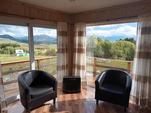 2 Stühle vor einem großen Fenster mit Aussicht in der Unterkunft Ventisca Sur in Coihaique