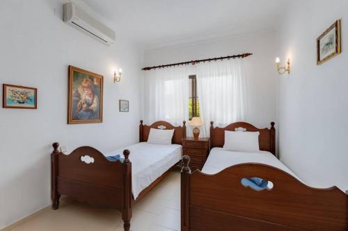 Duas camas num quarto com paredes brancas em VILLA ROSADO - Moradia para 6 com AC, jardim a 5 min do centro de Albufeira em Albufeira