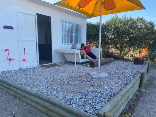 a woman sitting on a couch under an umbrella at The Beach Shack Glamping & The Boat Shed in St Helena Bay