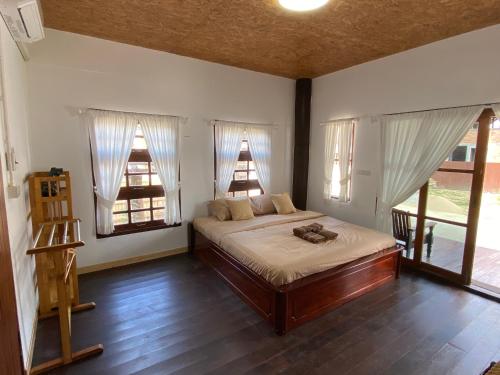a bedroom with a bed in a room with windows at บ้านทาคายามา in Ban Phae Khwang