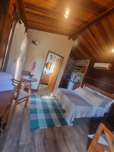 - une chambre avec un grand lit et une table dans l'établissement Chalé Tucano Recanto Buscapé SFX, à São Francisco Xavier