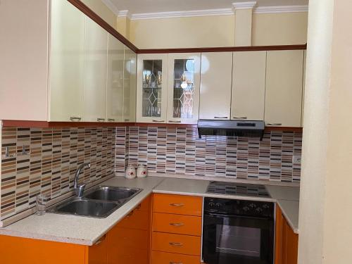 una cocina con armarios blancos y fregadero en Apartament pushimi, en Pogradec