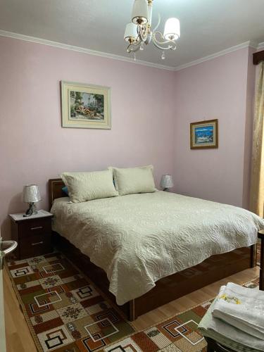 1 dormitorio con cama y lámpara de araña en Apartament pushimi, en Pogradec