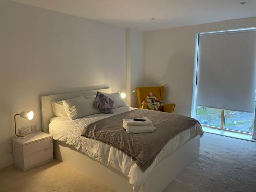 a white bedroom with a bed and a window at Lovely 2 Bedroom Apartment London in Woolwich