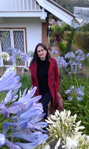 a woman standing next to a garden of flowers at Suítes no Chalé - Cabanas in Campos do Jordão