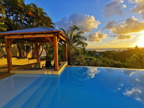 uma piscina com um gazebo num resort em Le Colibri d'isa em Capesterre-Belle-Eau