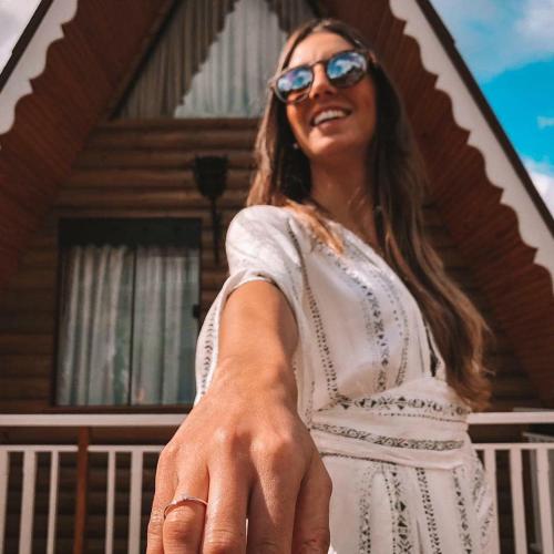a woman wearing sunglasses standing in front of a house at Suítes no Chalé - Cabanas in Campos do Jordão