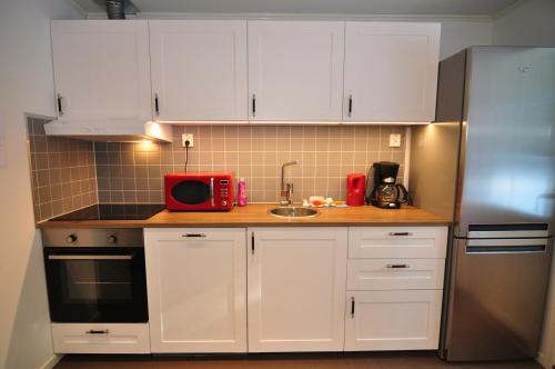 a kitchen with white cabinets and a red microwave at IGMA Lodge in Borlänge