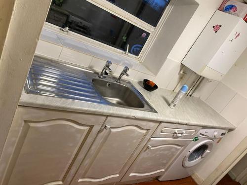 een keuken met een wastafel en een wasmachine bij Feel Like Your Home in Hastings
