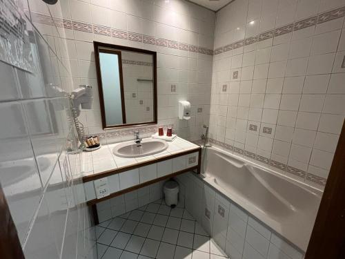 uma casa de banho com um lavatório, uma banheira e um espelho. em Albert 1er em Albertville
